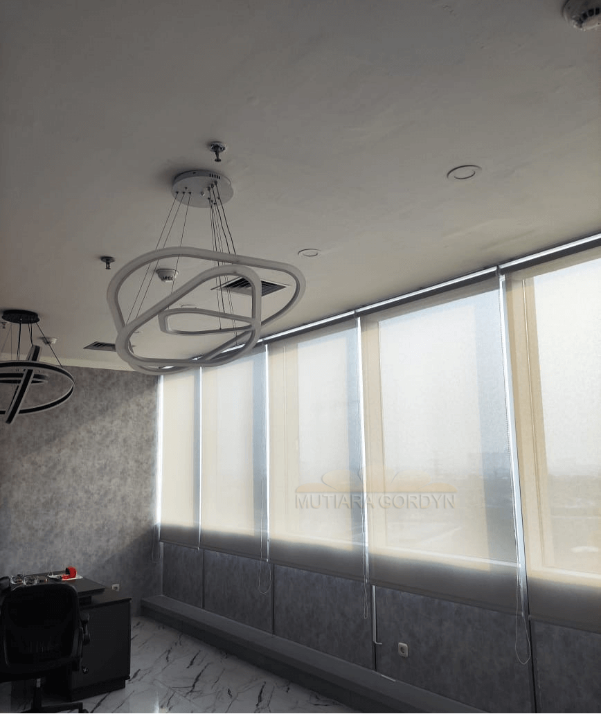 Aplikasi Roller Blind tipe Sunscreen warna putih tulang di area ruang keluarga, cahaya luar tetap masuk dengan lembut tanpa membuat ruangan terasa panas atau silau.