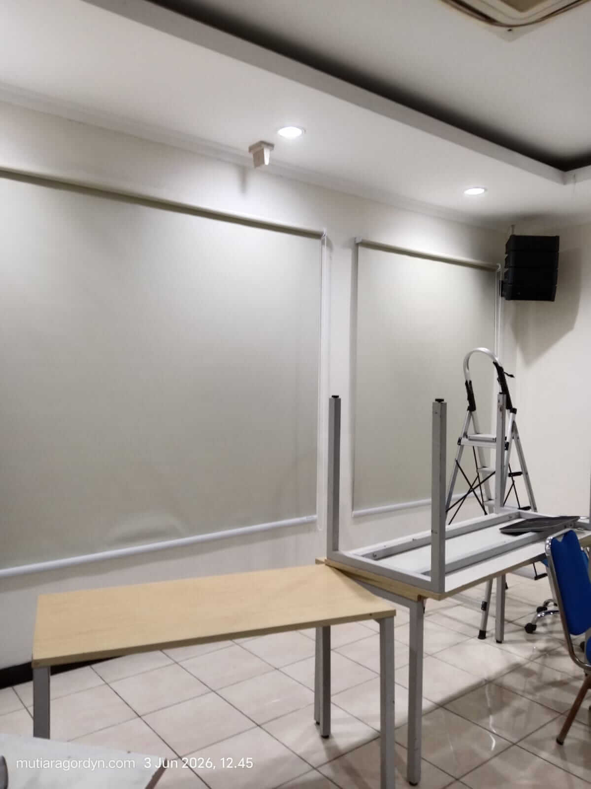 Pemasangan Roller Blind jenis Blackout warna abu-abu minimalis untuk ruang kerja ruko, memberikan perlindungan total dari terik matahari luar